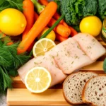 Fresh ingredients for pavé de saumon fumé, including salmon, fresh herbs, seasonal vegetables, lemon, olive oil, salt, pepper, and whole-grain bread