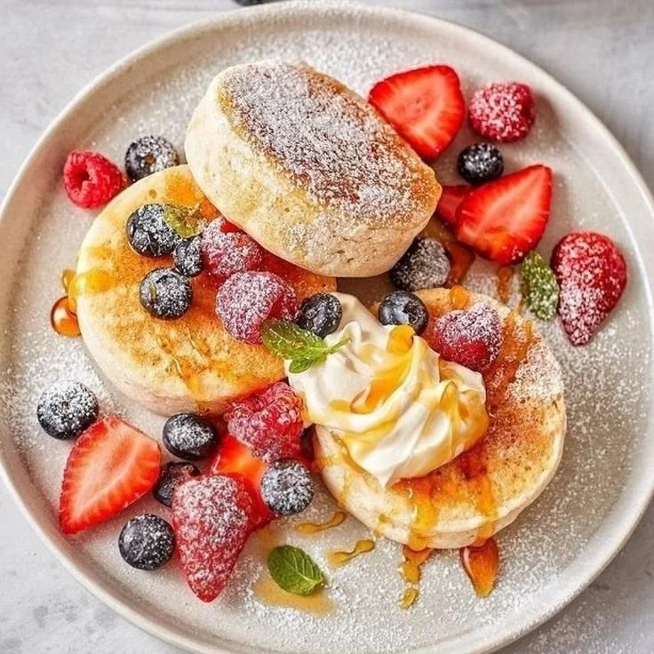 Pancakes aux baies fraîches dans une assiette, garnis de fruits et sirop