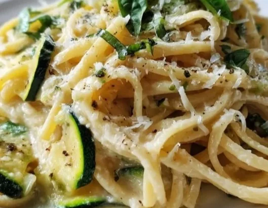 Pâtes aux courgettes et citron servies dans une assiette garnie de zeste de citron.