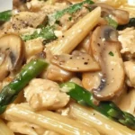 Penne avec poulet crémeux, champignons et asperges dans une assiette