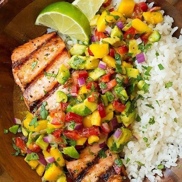 Saumon grillé avec salsa de mangue et riz à la noix de coco servi dans une assiette