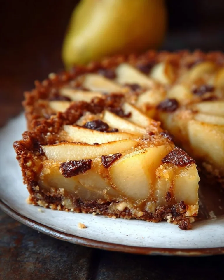 Tarte aux poires dorée garnie de poires juteuses et servie sur une assiette