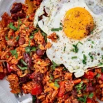 Plat de riz rouge aux épices cajun servi dans une assiette colorée.